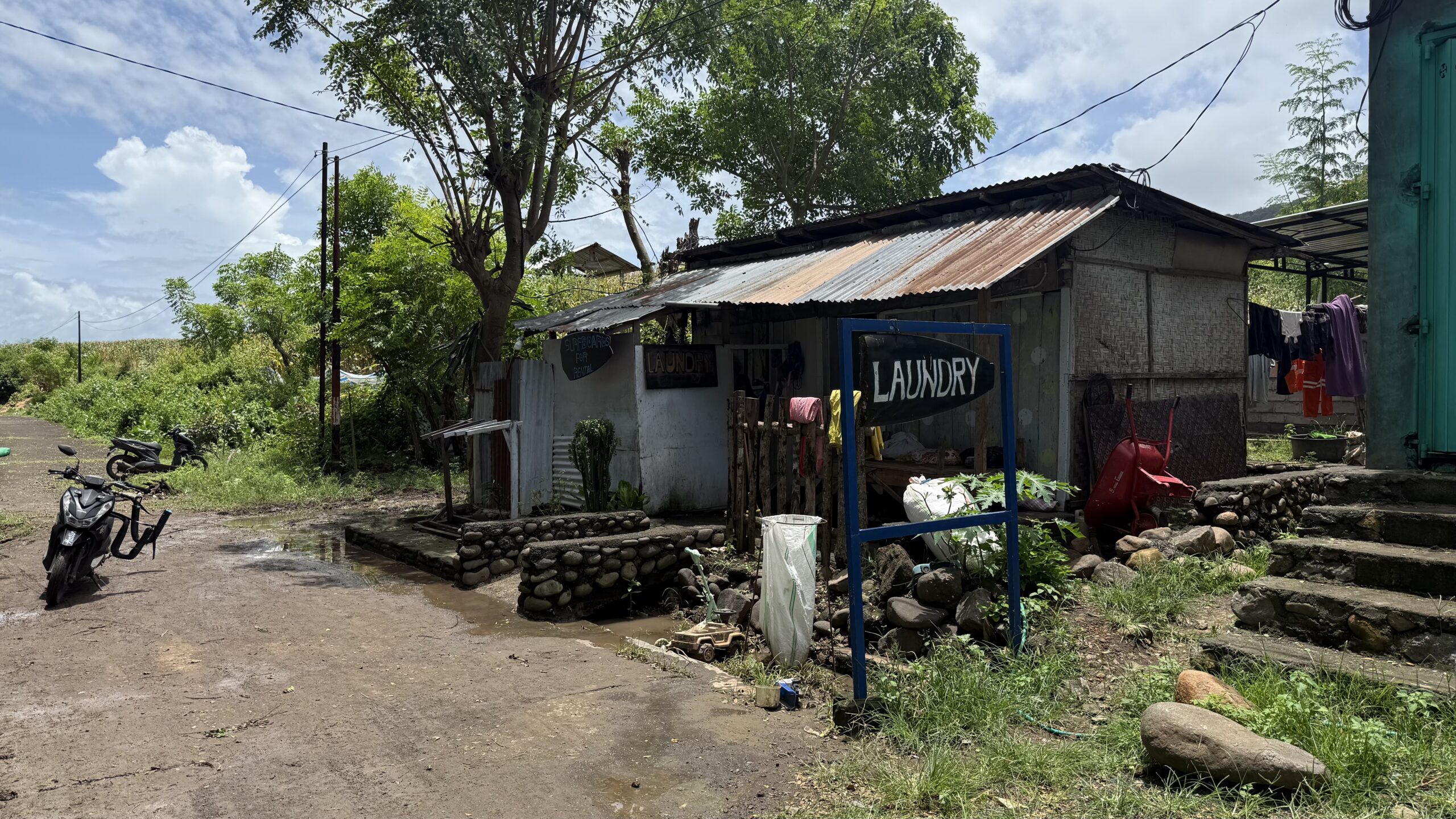 インドネシア スンバワ島のランドリー 周りは緑の多い路上店舗