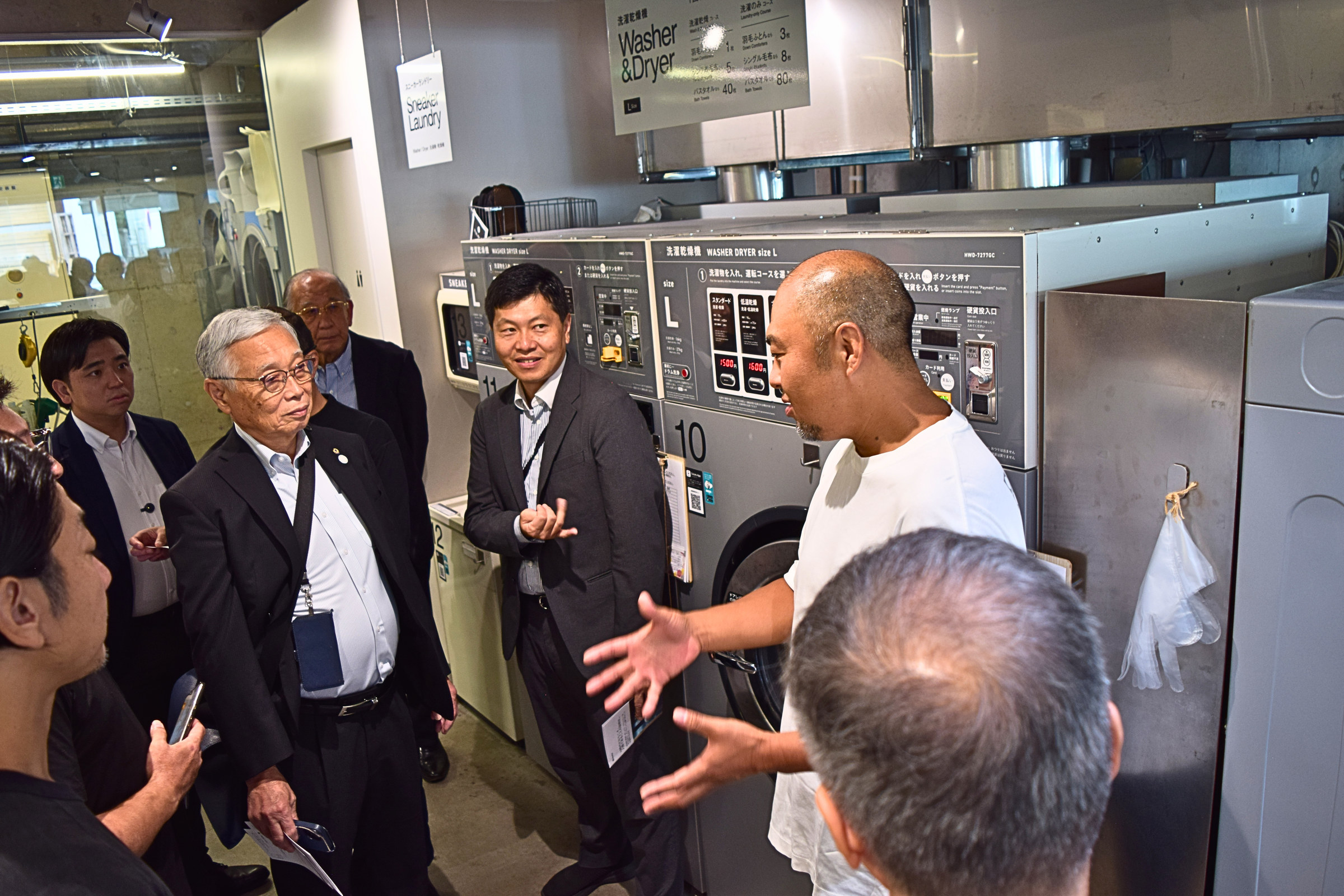 Baluko Laundry Place 代々木上原の店内でランドリー機器の説明を受ける視察参加者